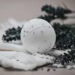White spherical candle with dark specks on a soft surface