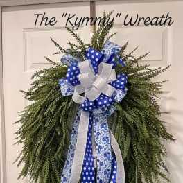 Green wreath with blue and white ribbon bow on a door