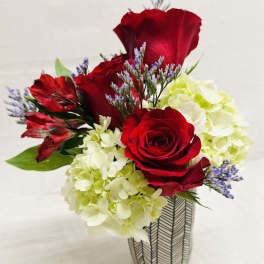 Red roses and pale hydrangeas arranged in a patterned vase