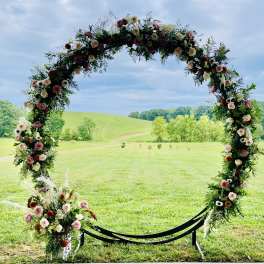 Floral arch with pink and cream flowers in an outdoor field