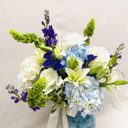 Blue and white floral arrangement in a marbled vase with a ribbon
