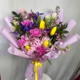 Bouquet of pink, yellow, and purple flowers wrapped in lavender paper
