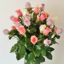 Tall glass vase of mixed pink, lavender, peach, and white roses with long stems