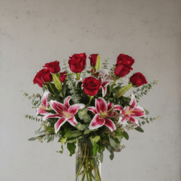 Red roses and pink lilies arranged in a clear glass vase