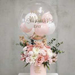 Pink floral arrangement with a clear Mother's Day balloon on a pink box
