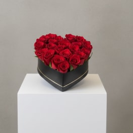 Heart-shaped box of red roses on a white pedestal
