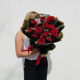 Large bouquet of red roses wrapped in black paper with gold trim