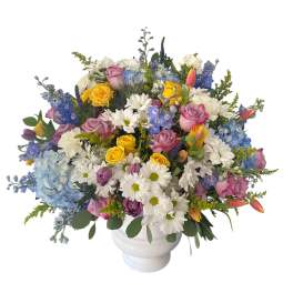 Mixed bouquet of roses, daisies, and hydrangeas in a white vase
