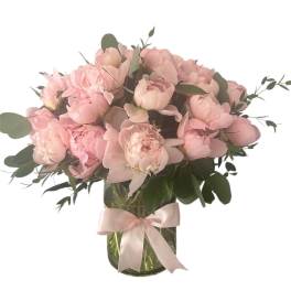 Pink peonies in a glass vase with a pale ribbon
