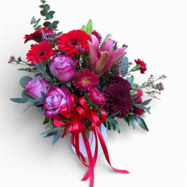 Pink and red mixed bouquet in a white vase with a ribbon