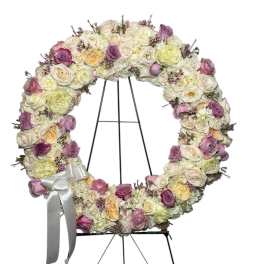 Circular floral wreath of pink, cream, and lavender roses on an easel