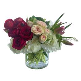 Bouquet of red and blush roses with white hydrangeas in a glass vase