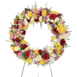 Circular floral wreath on a stand with roses, orchids, and lilies