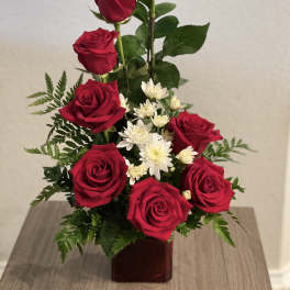 Red roses and white daisies arranged in a square vase