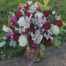 Bouquet of red and white roses with pink alstroemeria and daisies in a glass vase