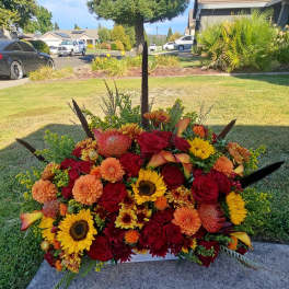 Large arrangement of red, orange, and yellow flowers in a low container