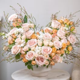 Large bouquet of pale pink and peach roses in a white vase