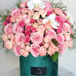Pink roses and carnations in a green velvet box with white orchids