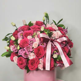 Pink rose bouquet in a round pink box with a pink candle beside it