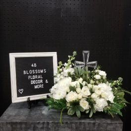 White floral arrangement with a clear glass cross and letter board