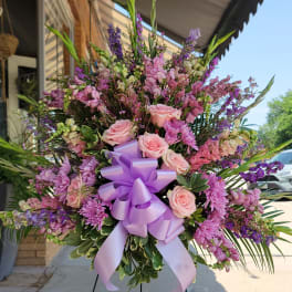 Large pink and purple floral standing spray with a lavender ribbon