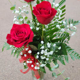 Three red roses in a clear vase with white baby's breath