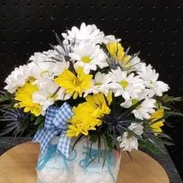 Yellow and white daisy bouquet in a decorative ceramic vase with a blue ribbon