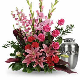 Pink and red floral funeral arrangement with a silver urn