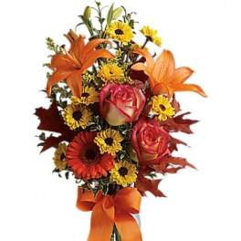 Bouquet of orange lilies, roses, and yellow daisies in a glass vase