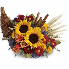 Sunflower bouquet with mixed fall flowers and wheat in a wicker cornucopia