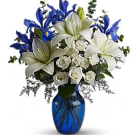 White lilies and roses with blue irises in a blue vase