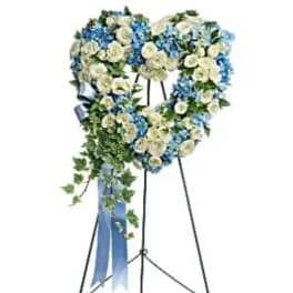 Heart-shaped floral standing spray with white and blue flowers on an easel