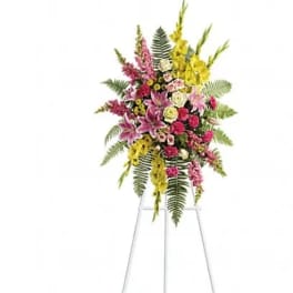 Tall floral standing spray with pink, yellow, and white flowers on a metal easel