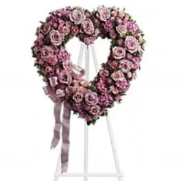Heart-shaped pink rose wreath on a standing easel with ribbon