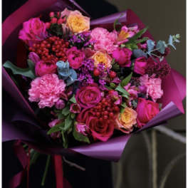Bouquet of pink and peach roses with carnations wrapped in purple paper