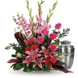 Pink roses and lilies arranged beside a silver urn