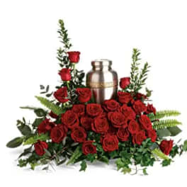 Red roses arranged around a silver urn with greenery
