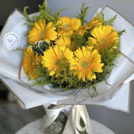 Yellow gerbera daisy bouquet wrapped in white paper