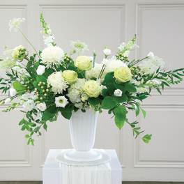 White and pale green floral arrangement in a white vase