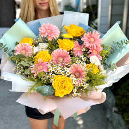 Bouquet of pink gerbera daisies and yellow roses wrapped in pastel paper