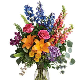 Colorful mixed bouquet in a clear glass vase with roses, lilies, and snapdragons