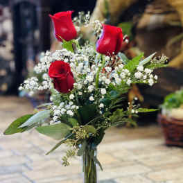 Red roses in a clear glass vase with white baby's breath