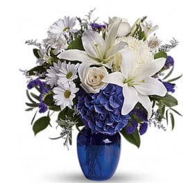 White lilies and daisies in a blue vase with purple accents