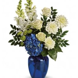 Blue vase with white and blue flowers and greenery