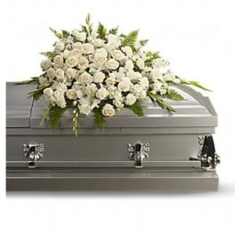 White floral casket spray on a gray casket