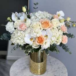 White and peach roses with orchids in a gold vase