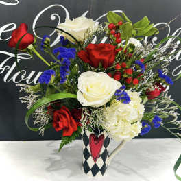 Bouquet of red and white roses with blue filler flowers in a patterned mug