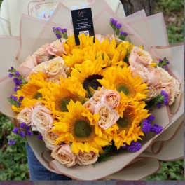 Bouquet of yellow sunflowers and pale peach roses wrapped in paper