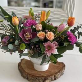 Mixed bouquet with tulips, roses, orchids, and chrysanthemums in a white vase