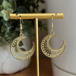 Pair of gold crescent moon earrings on a display stand
